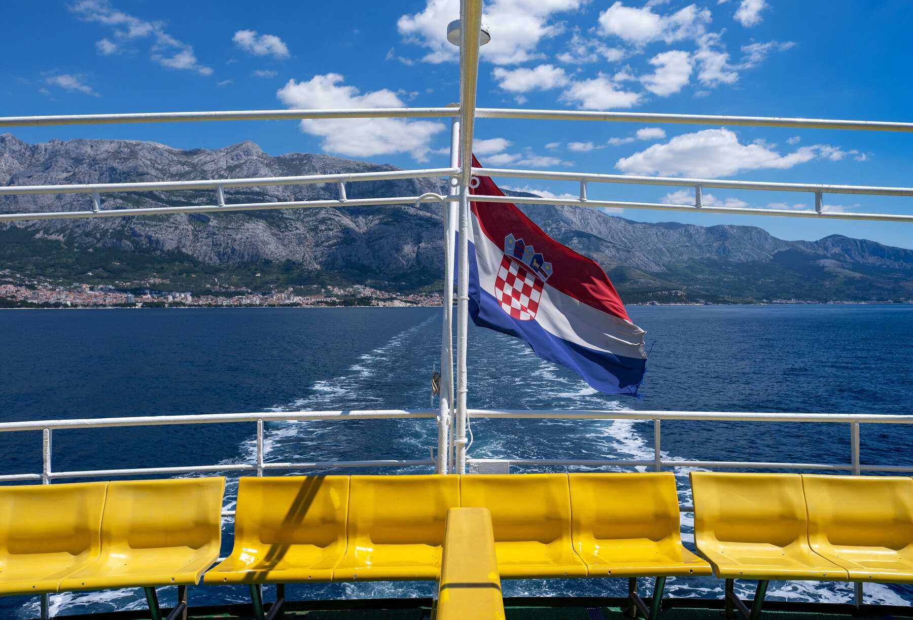 Le drapeau croate flotte à la poupe d'un car-ferry Jadrolinija, au départ de Makarska vers Sumartin, avec le massif du Biokovo en arrière-plan